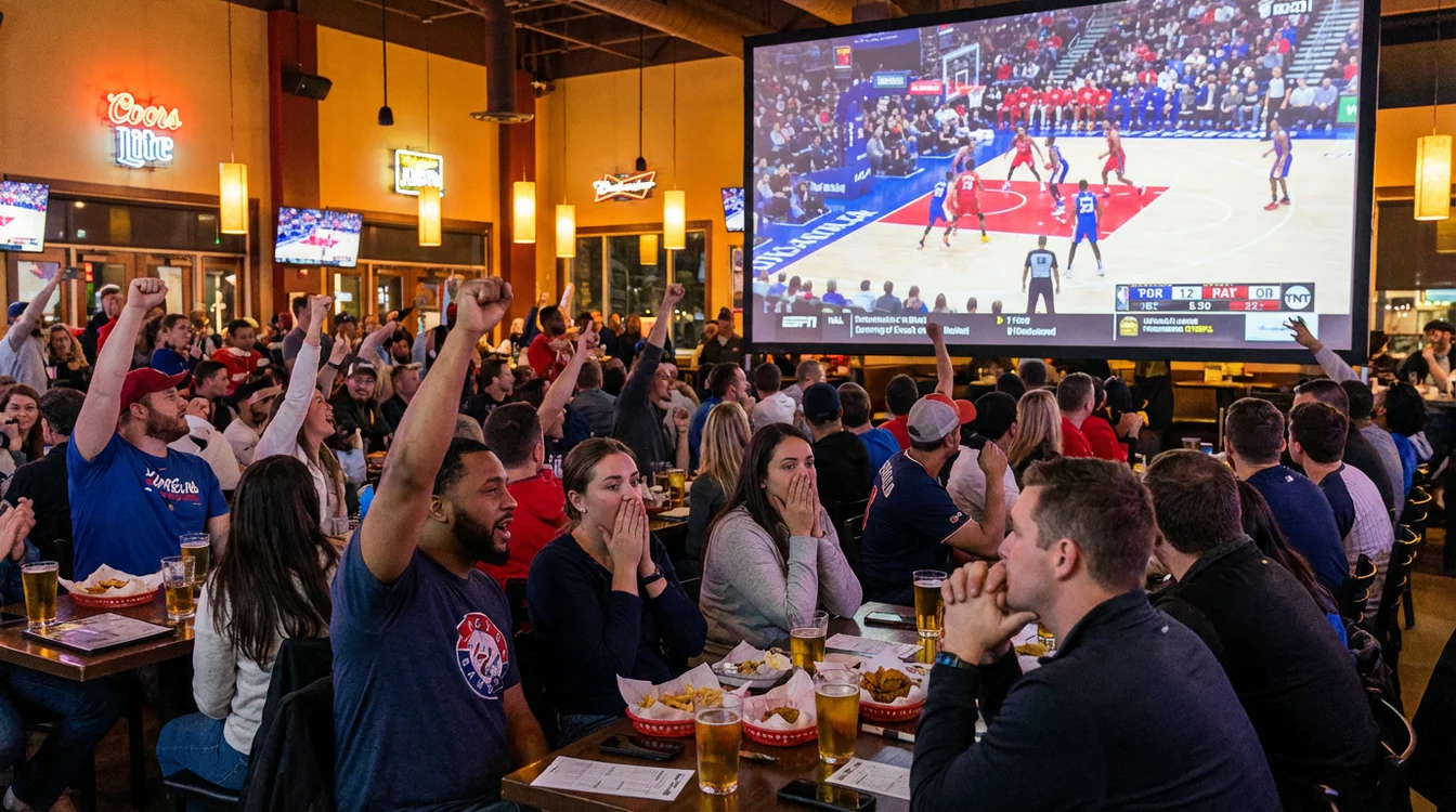 Tifosi che seguono una partita di basket su grande schermo con espressioni coinvolte